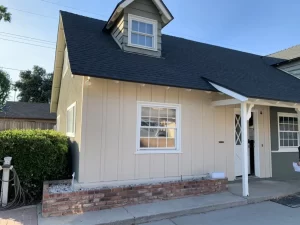 A charming beige house with a black roof, painted by professional painters in Riverside.