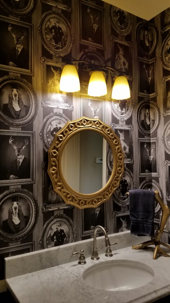 Before the wallpaper removal service, an eclectic bathroom in Riverside, CA showcases unique animal portraits wallpaper.