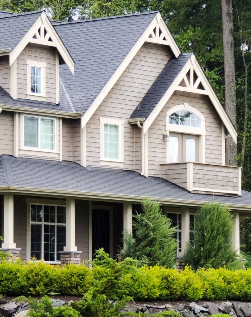 A newly painted beige house with dark trim, surrounded by greenery, completed by a painting company in Murrieta, CA.