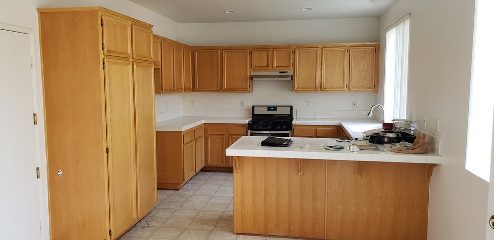 Neatly painted traditional kitchen in Riverside, with wooden cabinetry and ample natural light, enhanced by Victory Paints & Services Inc. Painting services in Riverside, CA.