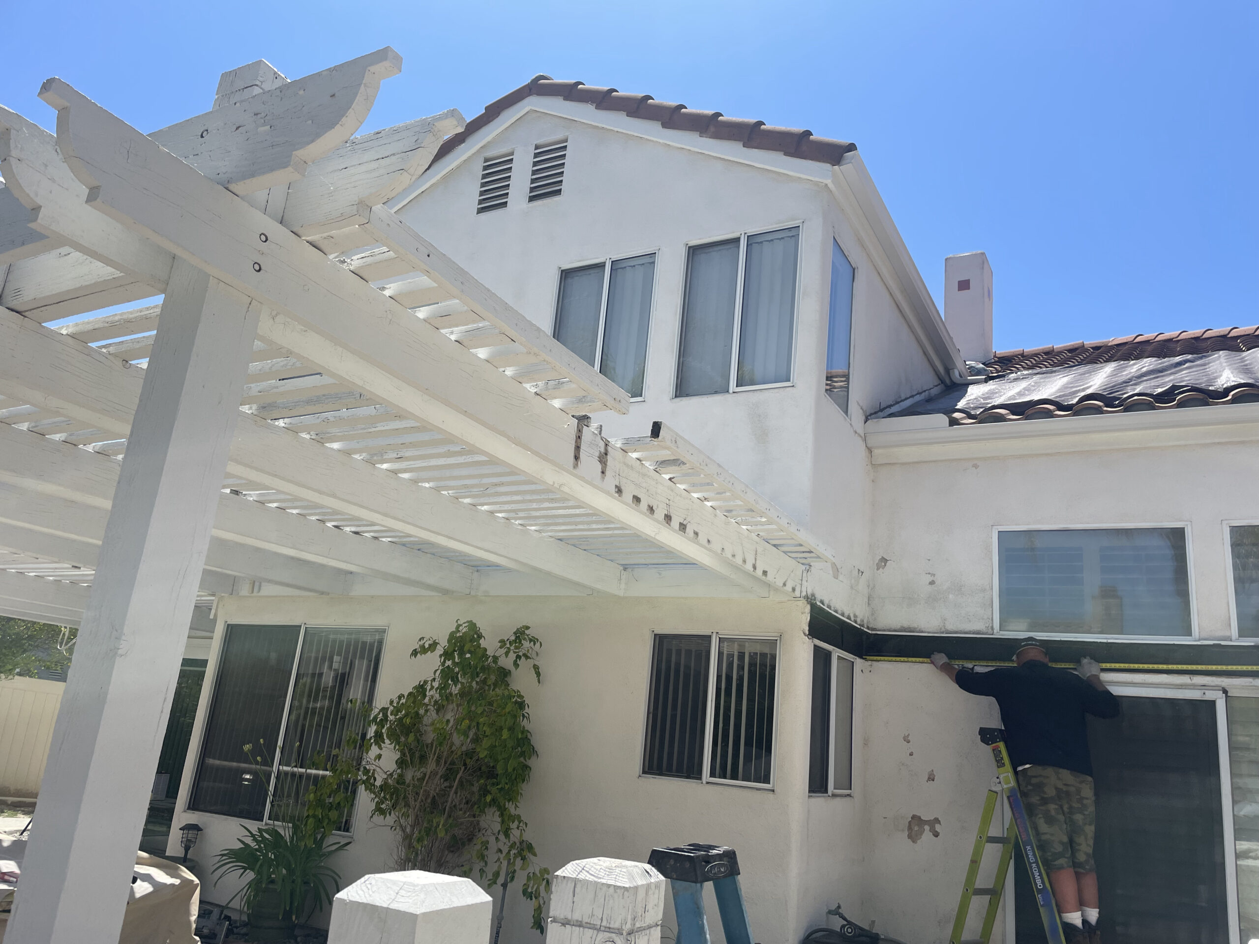 A two-story home undergoing exterior painting services in Moreno Valley, CA, with scaffolding and paint supplies visible.