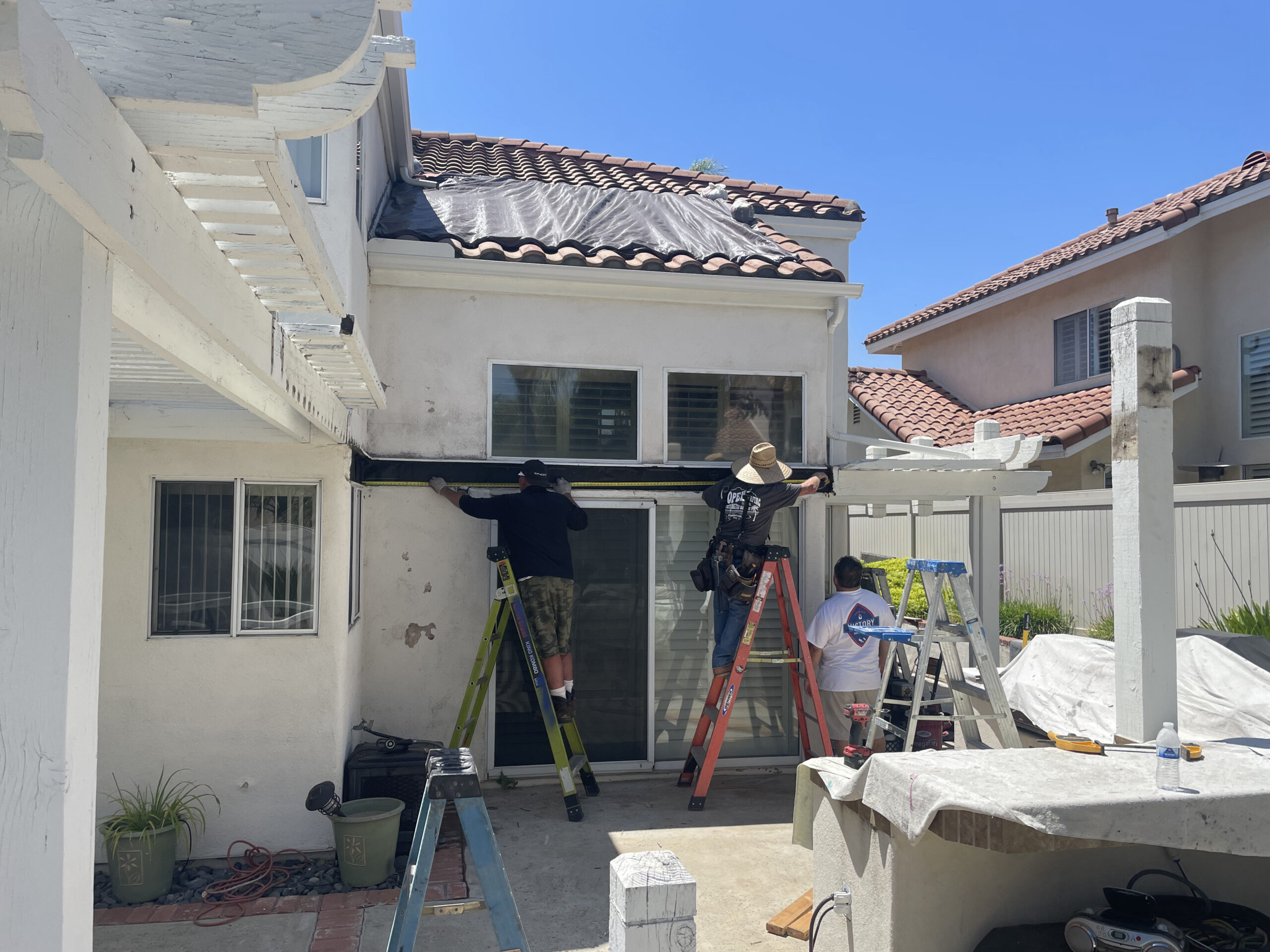 Exterior painting crew preparing and measuring a two-story home