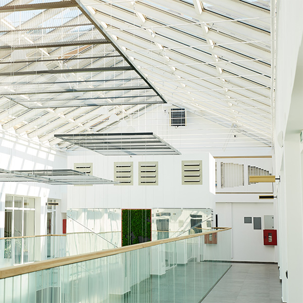 A bright, modern interior space with white walls, a glass railing, and a skylight ceiling, showcasing professional interior and exterior painting services in Woodcrest, CA.