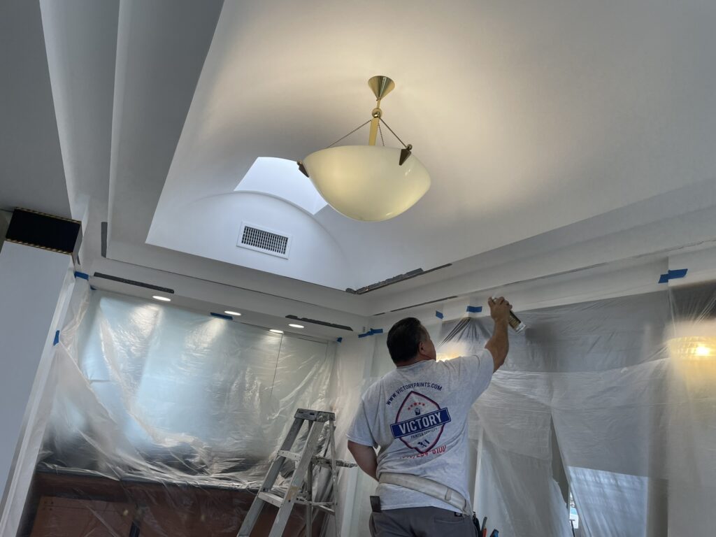 A professional painter from Victory Paints & Services Inc. preparing a ceiling for painting in a modern home, showcasing interior and exterior painting services in Orangecrest, CA.