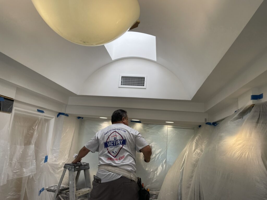 A professional painter working on an interior ceiling for a painting company in Woodcrest, CA.