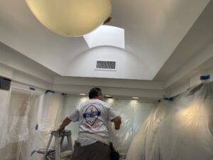 A professional painter working on an interior ceiling for a painting company in Woodcrest, CA.