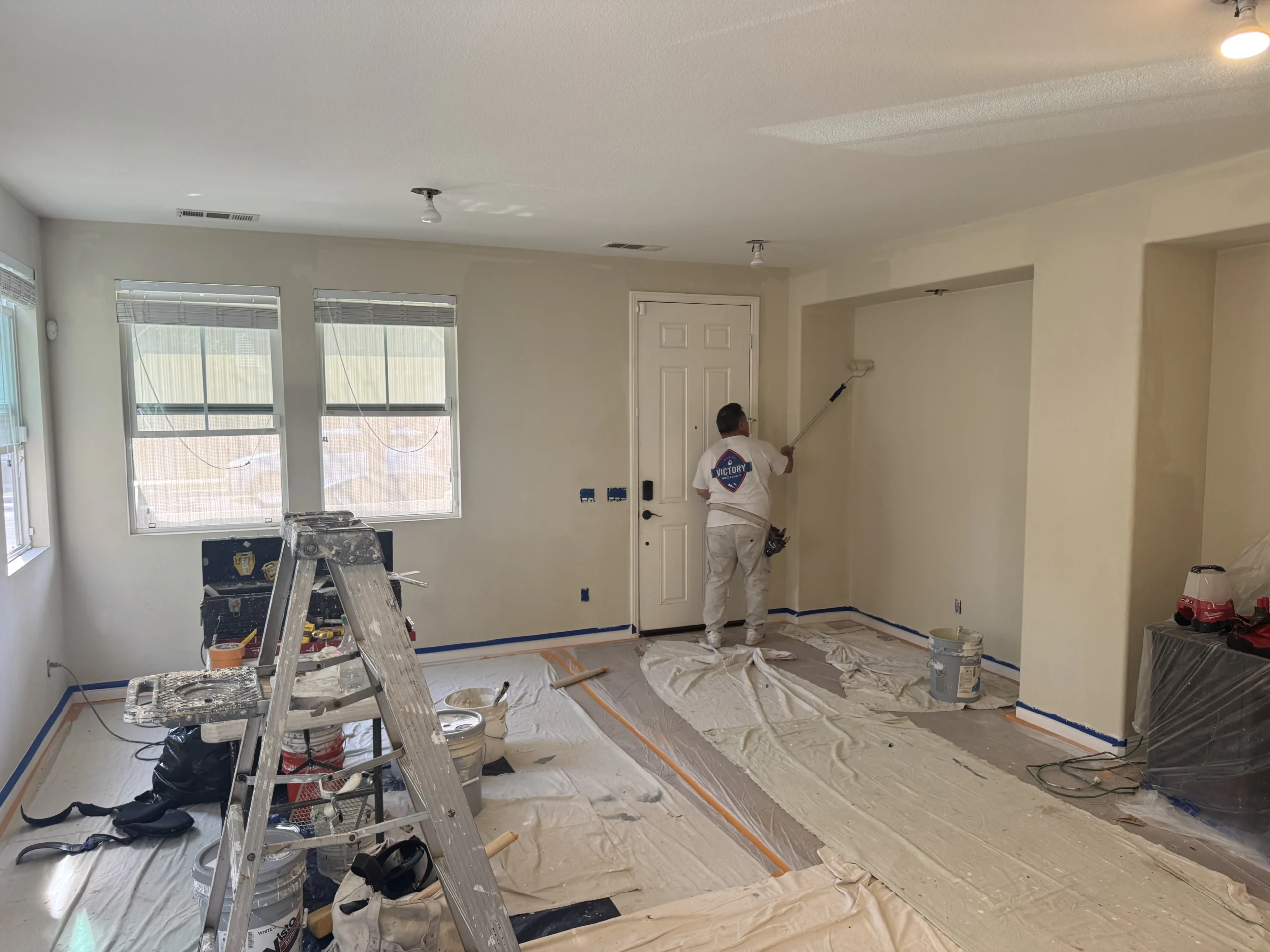 Professional painter preparing and painting walls in a living room